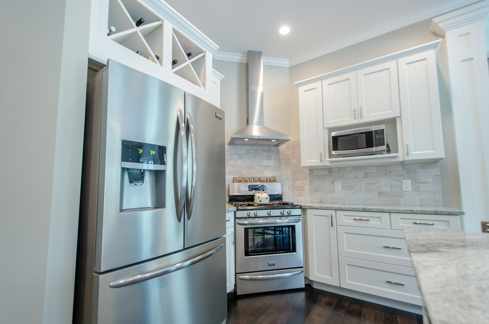 Example of a mid-sized transitional single-wall dark wood floor eat-in kitchen design with recessed-panel cabinets, white cabinets, granite countertops, stone tile backsplash, stainless steel appliances and an island