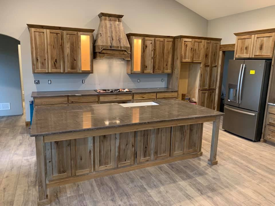 This is an example of an expansive country kitchen pantry in Kansas City with a farmhouse sink, shaker cabinets, light wood cabinets, granite benchtops, stainless steel appliances, light hardwood floors, with island, brown benchtop and vaulted.