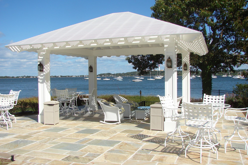Photo of a beach style backyard patio in New York with natural stone pavers and a pergola.