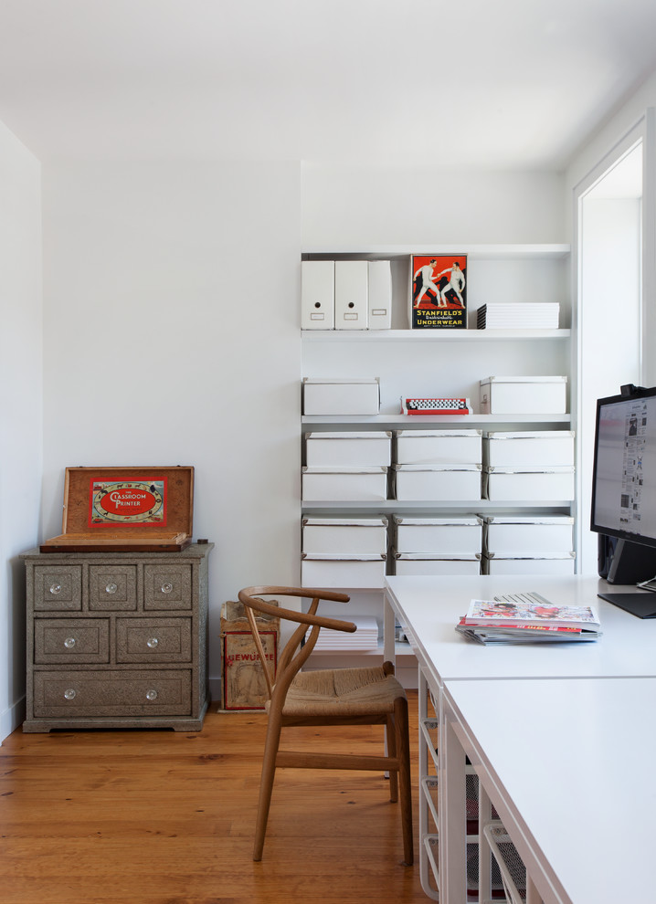 This is an example of a mid-sized contemporary home office in New York with white walls and a freestanding desk.