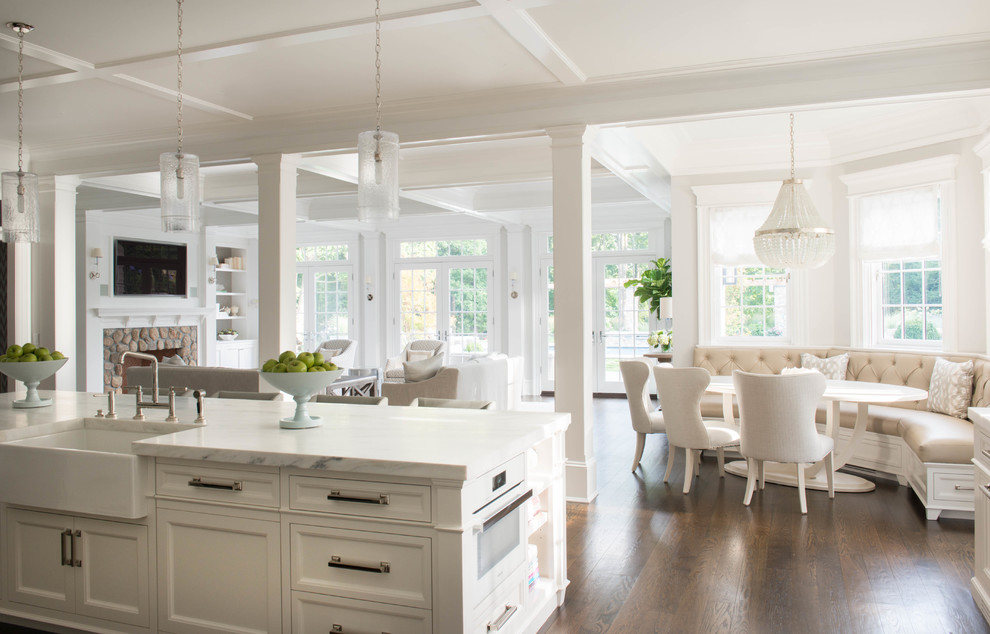 Design ideas for a large traditional galley eat-in kitchen in New York with a farmhouse sink, recessed-panel cabinets, white cabinets, marble benchtops, stainless steel appliances, dark hardwood floors and with island.