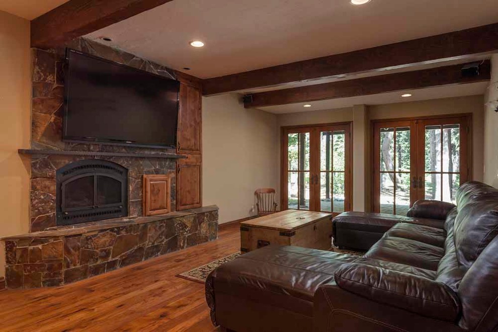 Photo of a large arts and crafts enclosed family room in Sacramento with a library, medium hardwood floors, a standard fireplace, a stone fireplace surround and a built-in media wall.