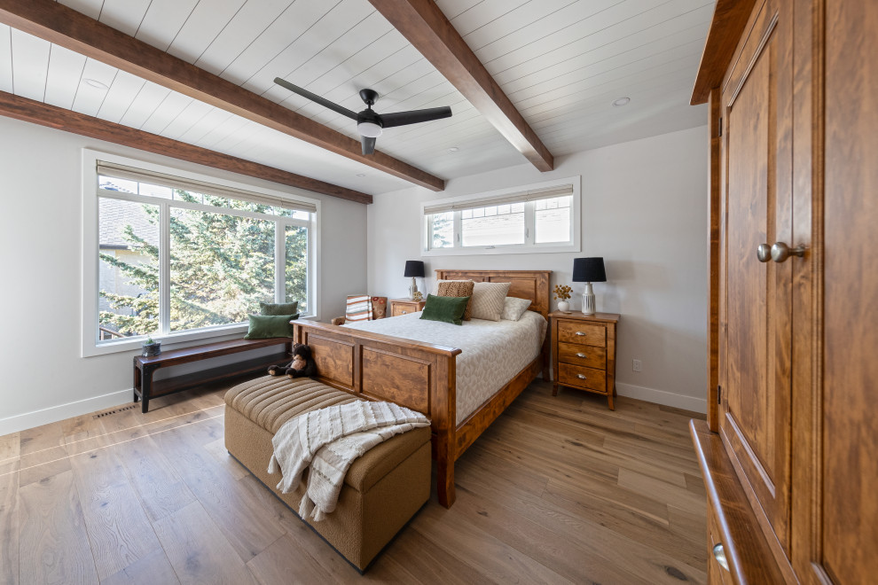 Imagen de dormitorio principal de estilo de casa de campo de tamaño medio con paredes blancas, suelo vinílico, suelo marrón y machihembrado