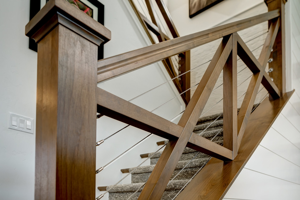 Inspiration for a mid-sized country carpeted u-shaped staircase in Boise with carpet risers and wood railing.