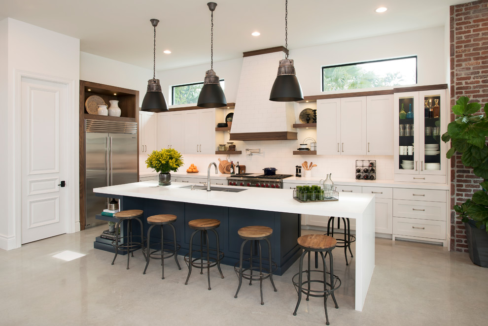 Design ideas for a mid-sized industrial l-shaped open plan kitchen in Miami with a double-bowl sink, shaker cabinets, beige cabinets, quartz benchtops, beige splashback, ceramic splashback, stainless steel appliances, concrete floors and with island.