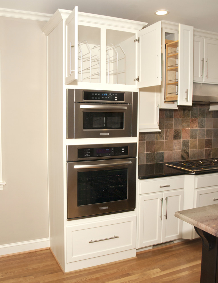 Kitchen - large transitional medium tone wood floor kitchen idea with an undermount sink, recessed-panel cabinets, white cabinets, granite countertops, multicolored backsplash, stone tile backsplash, stainless steel appliances and an island