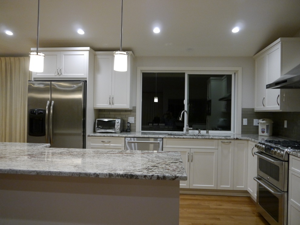 Kitchen - transitional kitchen idea in Seattle with an undermount sink, shaker cabinets, white cabinets, granite countertops, gray backsplash and an island