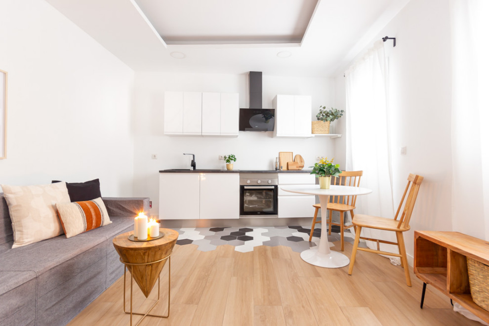 Modelo de sala de estar tipo loft industrial pequeña sin televisor con paredes blancas, suelo de madera en tonos medios y suelo marrón