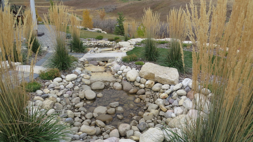 Inspiration for a large traditional backyard garden for fall in Calgary with with pond and concrete pavers.