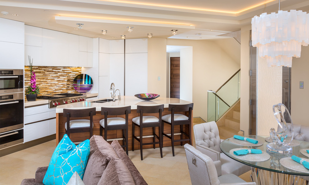 This is an example of a beach style open plan kitchen in Orange County with a double-bowl sink, flat-panel cabinets, white cabinets, multi-coloured splashback, matchstick tile splashback, stainless steel appliances, with island and beige floor.