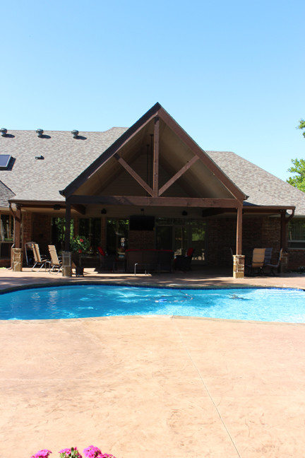 Inspiration for a large traditional backyard verandah in Oklahoma City with stamped concrete and a roof extension.
