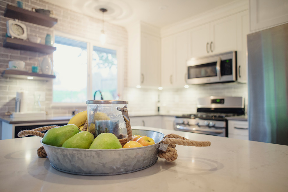 Open concept kitchen - mid-sized transitional l-shaped open concept kitchen idea in Vancouver with an undermount sink, shaker cabinets, white cabinets, quartz countertops, gray backsplash, stainless steel appliances and an island