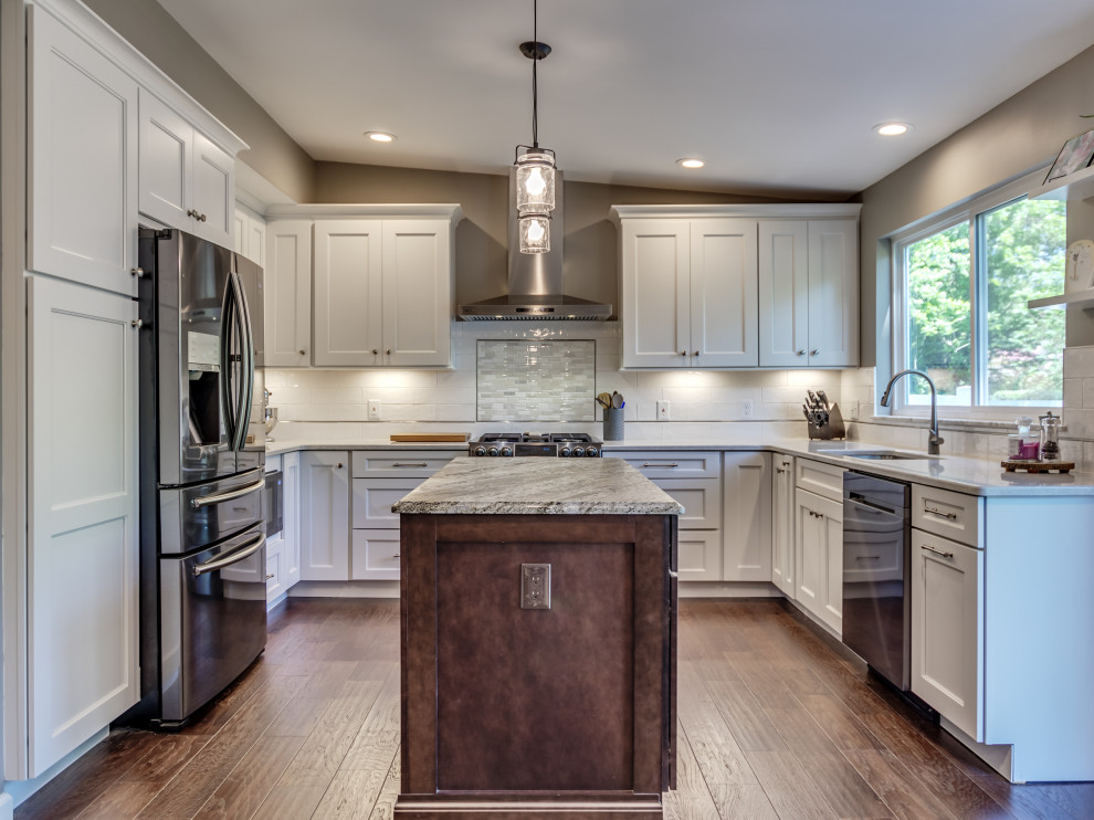 Inspiration for a mid-sized transitional u-shaped eat-in kitchen in St Louis with white cabinets, white splashback, subway tile splashback, stainless steel appliances, with island, brown floor, granite benchtops and multi-coloured benchtop.