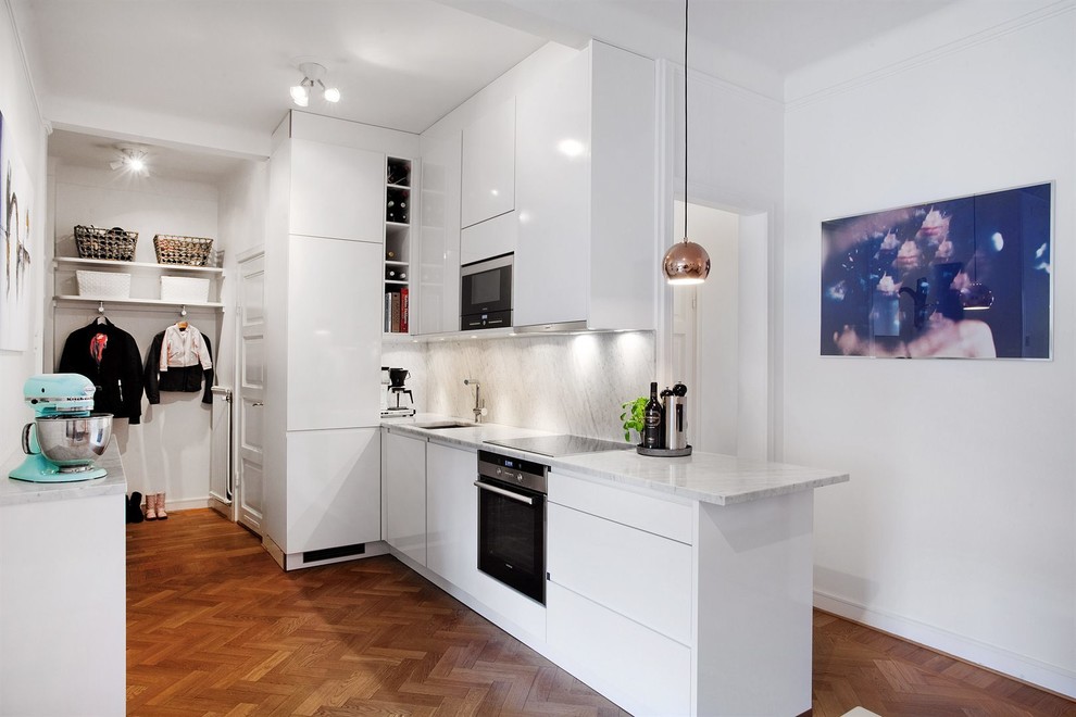 Mid-sized scandinavian galley separate kitchen in Stockholm with an undermount sink, flat-panel cabinets, white cabinets, stainless steel appliances, light hardwood floors, marble benchtops and no island.