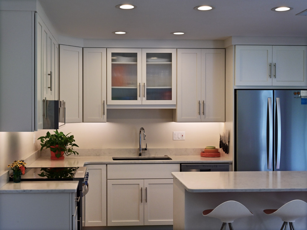 Example of a small transitional l-shaped light wood floor open concept kitchen design with an undermount sink, shaker cabinets, white cabinets, quartz countertops, an island and white countertops