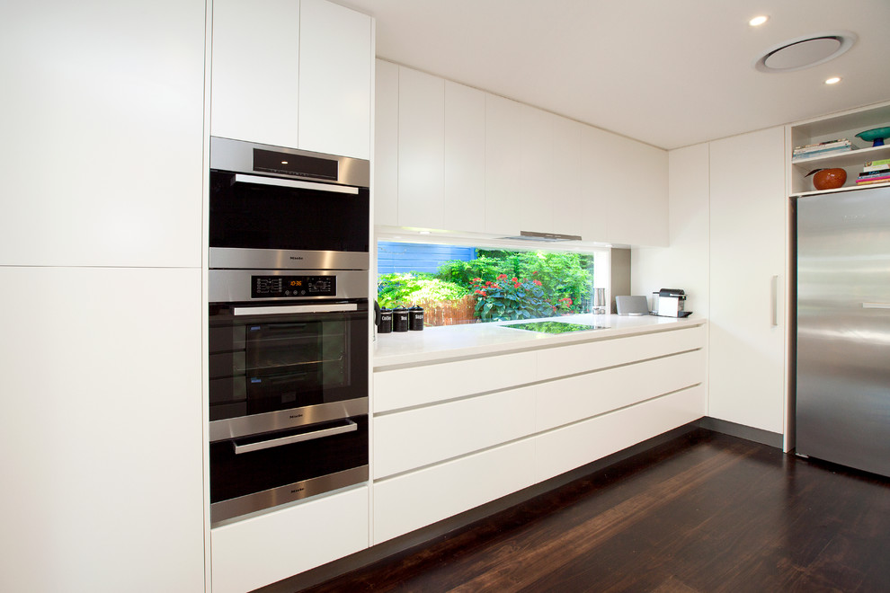Inspiration for a large contemporary galley eat-in kitchen in Brisbane with a double-bowl sink, flat-panel cabinets, white cabinets, quartz benchtops, brown splashback, glass tile splashback, stainless steel appliances, with island and dark hardwood floors.