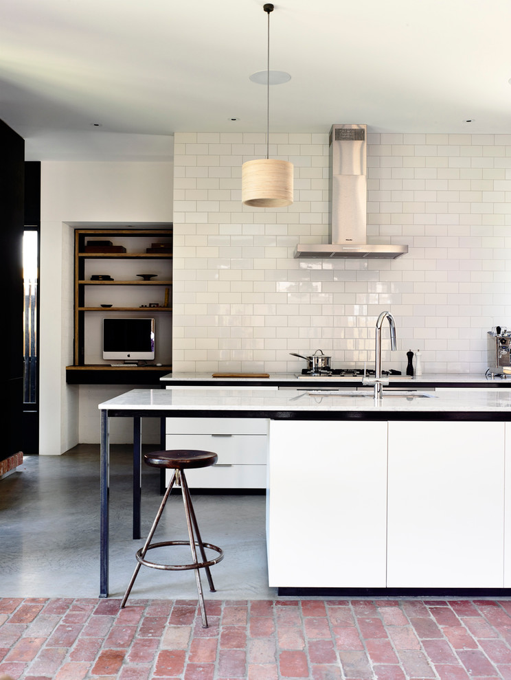 This is an example of a mid-sized contemporary galley eat-in kitchen in Melbourne with with island, flat-panel cabinets, concrete floors, an undermount sink, quartz benchtops, white splashback, subway tile splashback and stainless steel appliances.