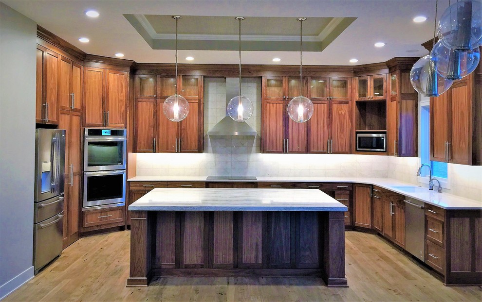 Eat-in kitchen - large transitional u-shaped light wood floor and brown floor eat-in kitchen idea in Omaha with an undermount sink, shaker cabinets, medium tone wood cabinets, quartz countertops, white backsplash, subway tile backsplash, stainless steel appliances, an island and white countertops