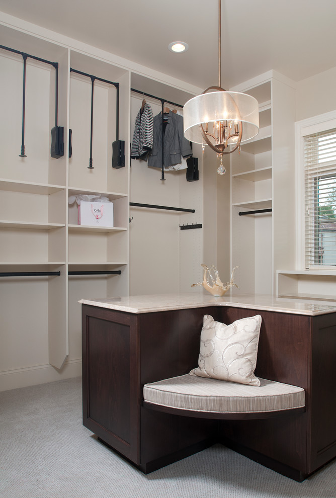 Photo of an expansive mediterranean gender-neutral dressing room in Grand Rapids with recessed-panel cabinets, dark wood cabinets and carpet.