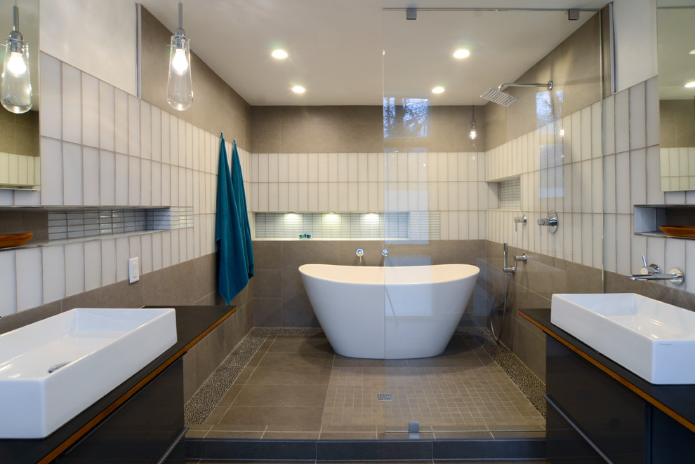 This is an example of a large modern master wet room bathroom in Raleigh with flat-panel cabinets, grey cabinets, a freestanding tub, a wall-mount toilet, gray tile, ceramic tile, white walls, ceramic floors, a vessel sink, grey floor, an open shower and wood benchtops.