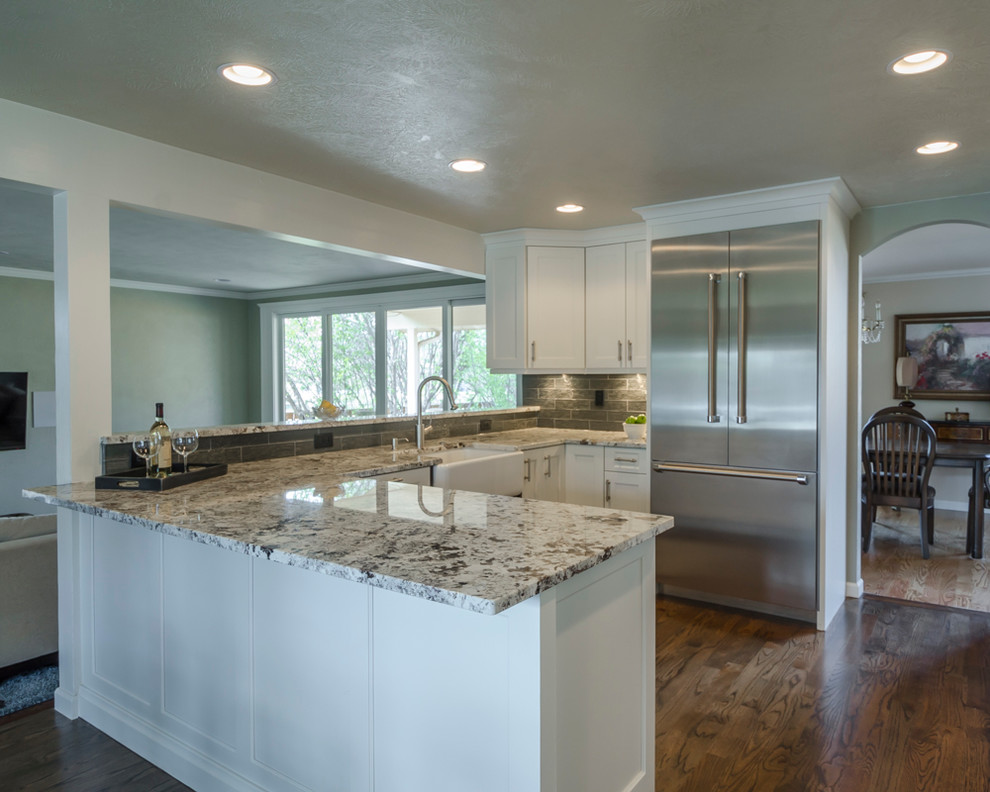 Inspiration for a mid-sized transitional u-shaped medium tone wood floor eat-in kitchen remodel in Denver with a farmhouse sink, shaker cabinets, white cabinets, laminate countertops, green backsplash, glass tile backsplash, stainless steel appliances and a peninsula