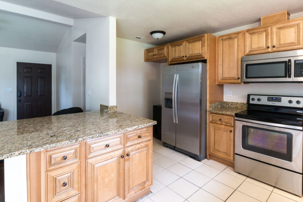 Mid-sized l-shaped eat-in kitchen photo with an undermount sink, raised-panel cabinets, medium tone wood cabinets, granite countertops, ceramic backsplash, stainless steel appliances, a peninsula and brown countertops
