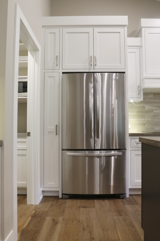 Open concept kitchen - large transitional l-shaped dark wood floor open concept kitchen idea in Grand Rapids with an undermount sink, shaker cabinets, white cabinets, quartz countertops, beige backsplash, porcelain backsplash, stainless steel appliances and an island