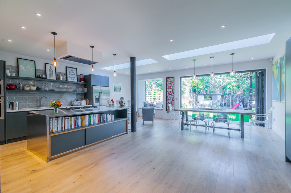 Photo of a mid-sized contemporary open plan kitchen in Surrey with an integrated sink, flat-panel cabinets, grey cabinets, stainless steel benchtops, grey splashback, porcelain splashback, stainless steel appliances, medium hardwood floors and with island.
