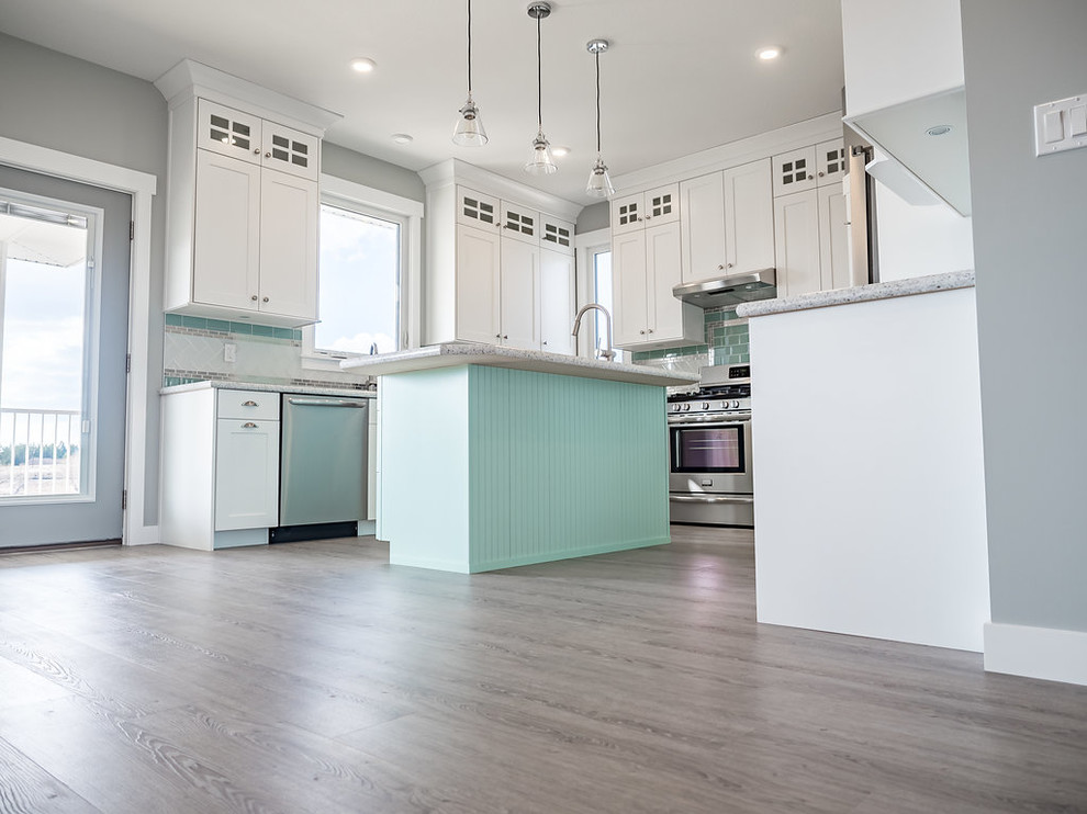 Design ideas for a mid-sized traditional u-shaped kitchen in Edmonton with a double-bowl sink, raised-panel cabinets, white cabinets, quartz benchtops, green splashback, subway tile splashback, stainless steel appliances, vinyl floors, with island and grey floor.