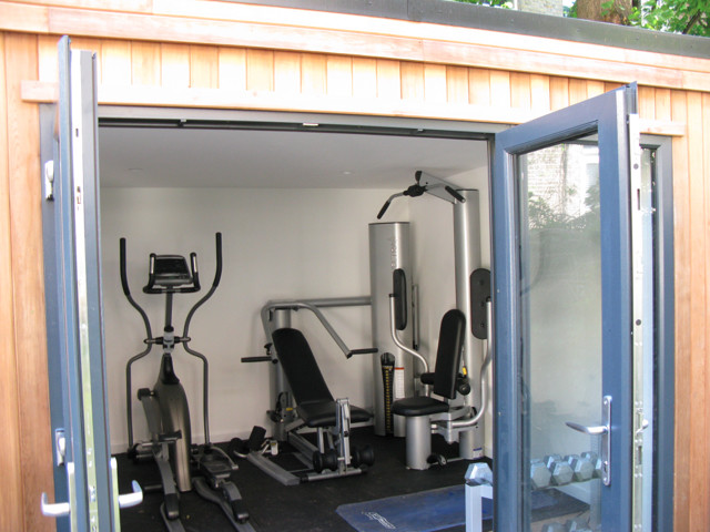 This is an example of a mid-sized contemporary multipurpose gym in Other with white walls and light hardwood floors.