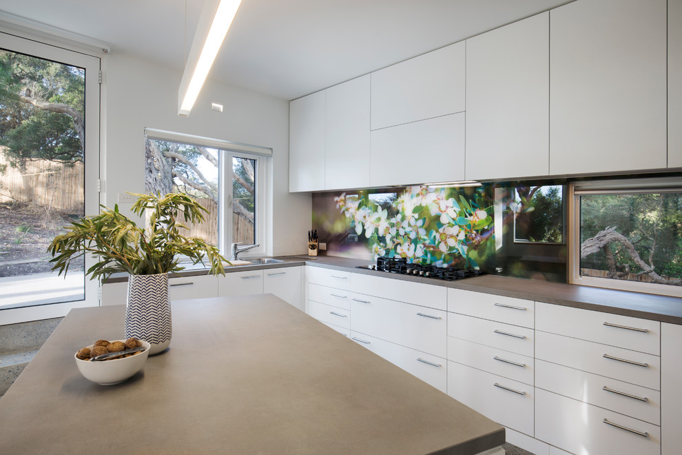Inspiration for a large contemporary u-shaped open plan kitchen in Melbourne with a double-bowl sink, white cabinets, concrete benchtops, multi-coloured splashback, glass sheet splashback, concrete floors, with island, grey floor and grey benchtop.