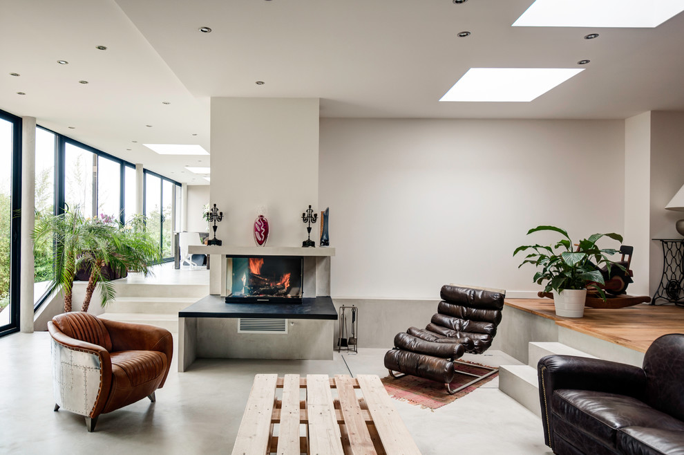 This is an example of an expansive contemporary formal open concept living room in Paris with concrete floors, white walls, a concrete fireplace surround, a standard fireplace and no tv.