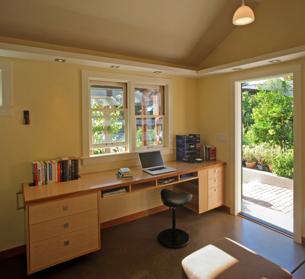 Photo of a small country home office in San Francisco with yellow walls, concrete floors, a built-in desk and no fireplace.