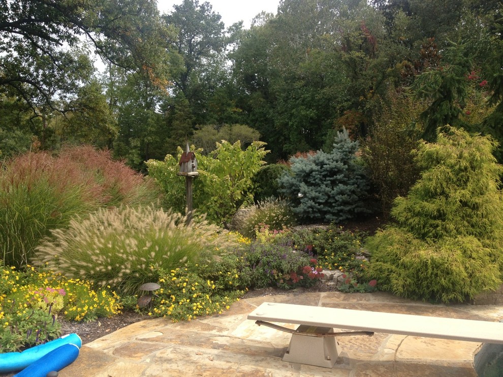 Large traditional backyard full sun garden in St Louis with a garden path and natural stone pavers for spring.
