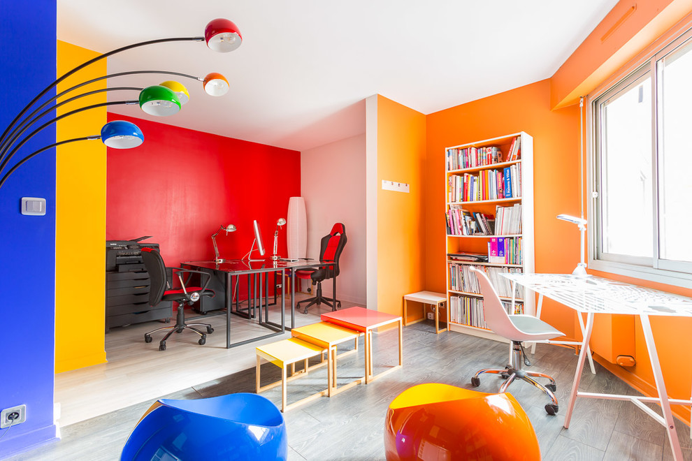 This is an example of a mid-sized eclectic home office in Paris with a library, multi-coloured walls, medium hardwood floors, a freestanding desk and grey floor.