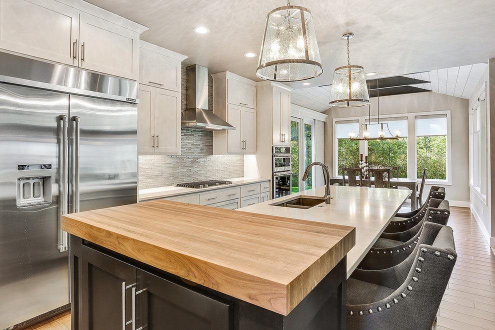 Example of a transitional single-wall dark wood floor and brown floor kitchen design with an undermount sink, shaker cabinets, quartz countertops, glass tile backsplash, an island and stainless steel appliances