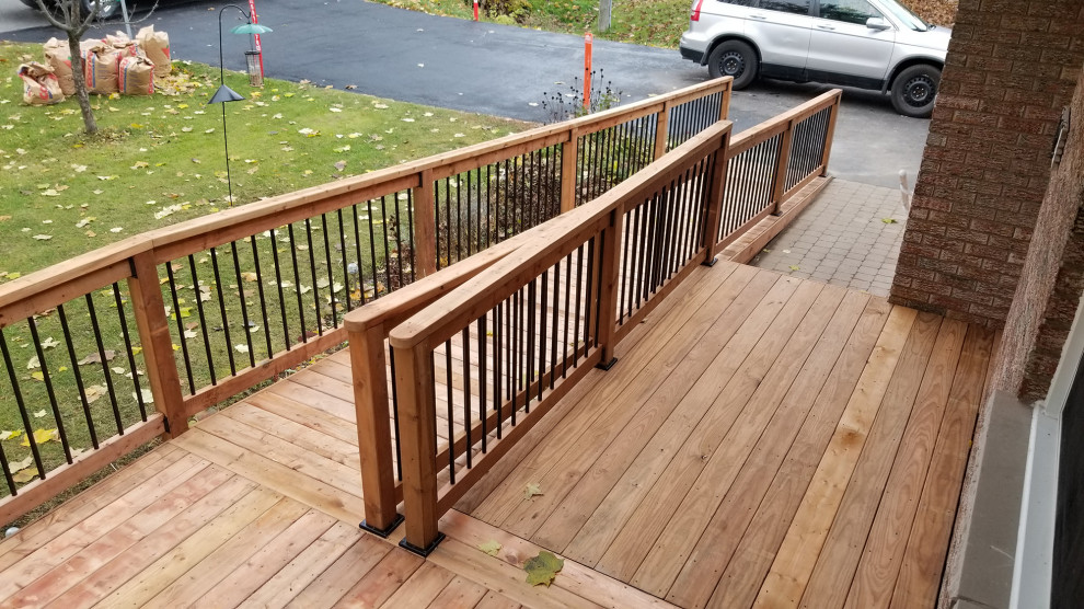 Mid-sized modern ground level deck in Ottawa with with skirting, no cover and mixed railing.