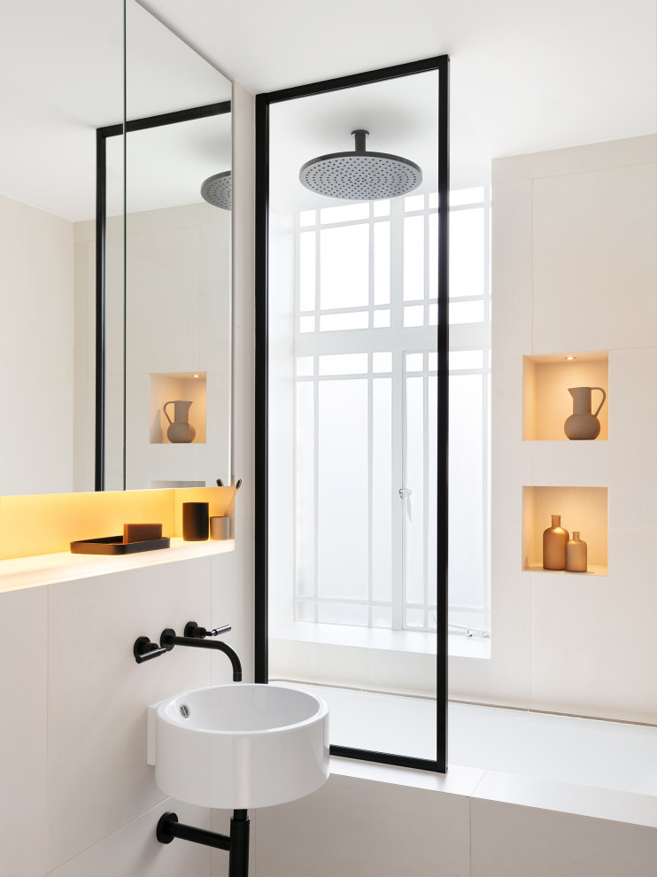 Photo of a small contemporary kids bathroom in London with beige cabinets, a drop-in tub, a curbless shower, a wall-mount toilet, beige tile, ceramic tile, beige walls, ceramic floors, black floor, a single vanity and a built-in vanity.