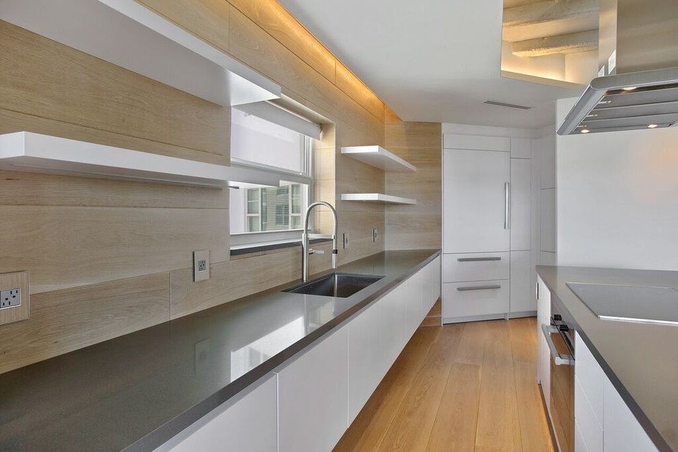 This is an example of an expansive contemporary single-wall open plan kitchen in Miami with open cabinets, white cabinets, beige splashback, stainless steel appliances, light hardwood floors, with island, an undermount sink, concrete benchtops and porcelain splashback.