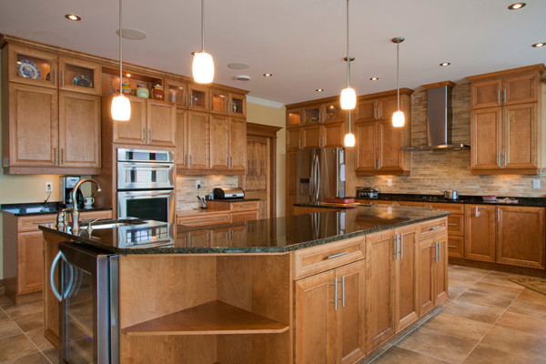 Example of a ceramic tile kitchen design with a double-bowl sink, recessed-panel cabinets, medium tone wood cabinets, multicolored backsplash, ceramic backsplash, stainless steel appliances and an island