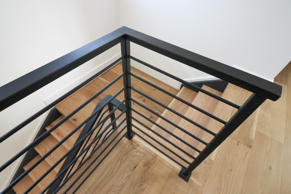Ejemplo de escalera recta actual de tamaño medio con escalones de madera y barandilla de metal