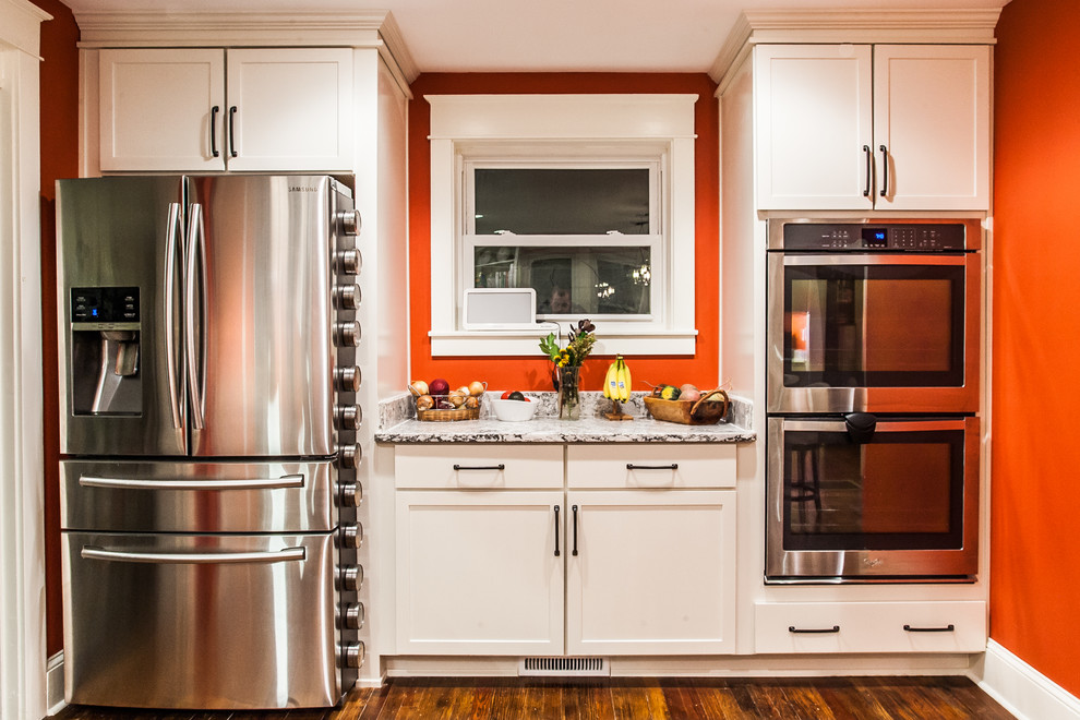 Example of a large transitional u-shaped light wood floor and brown floor enclosed kitchen design in Baltimore with an undermount sink, shaker cabinets, white cabinets, gray backsplash, subway tile backsplash, stainless steel appliances, an island and quartz countertops