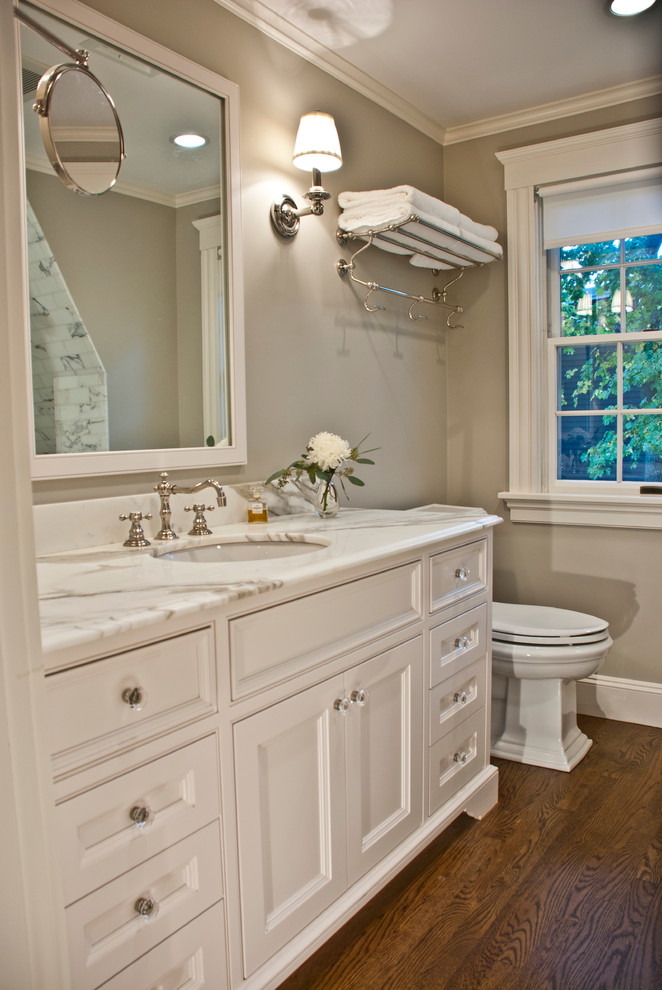 Inspiration for a mid-sized traditional master bathroom in Boston with marble benchtops, an undermount sink, white cabinets, white tile, stone tile, beige walls, dark hardwood floors and recessed-panel cabinets.