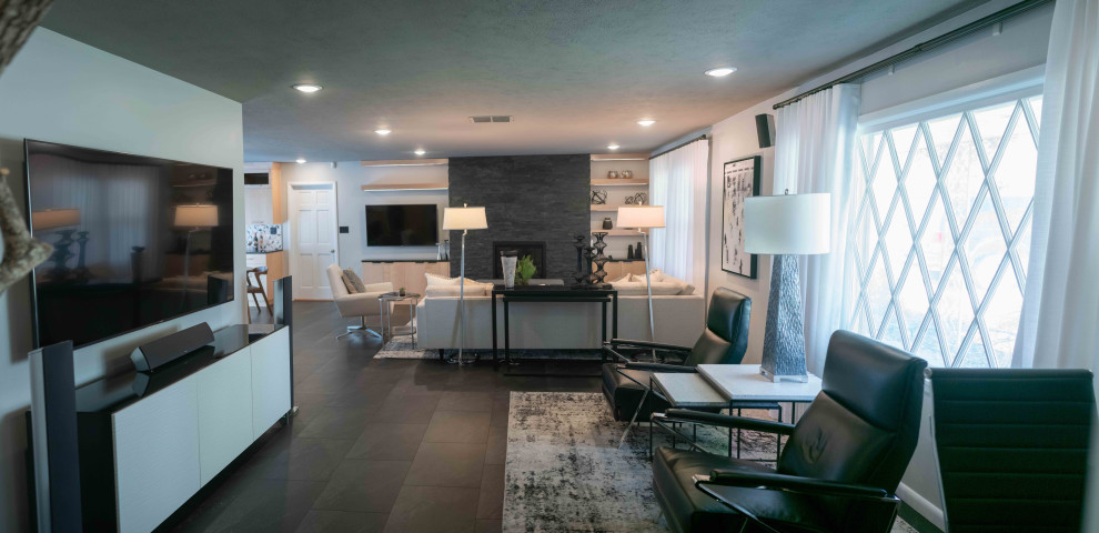 Photo of a large midcentury open concept living room in Other with grey walls, vinyl floors, a standard fireplace, a stone fireplace surround and black floor.