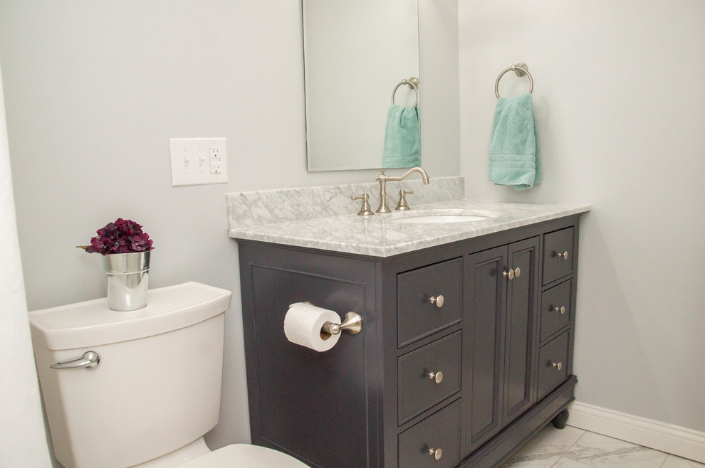 This is an example of a small transitional 3/4 bathroom in Louisville with a two-piece toilet, beige tile, grey walls, an undermount sink, marble benchtops, recessed-panel cabinets, dark wood cabinets, an alcove tub, a shower/bathtub combo, ceramic tile, marble floors, white floor and a shower curtain.
