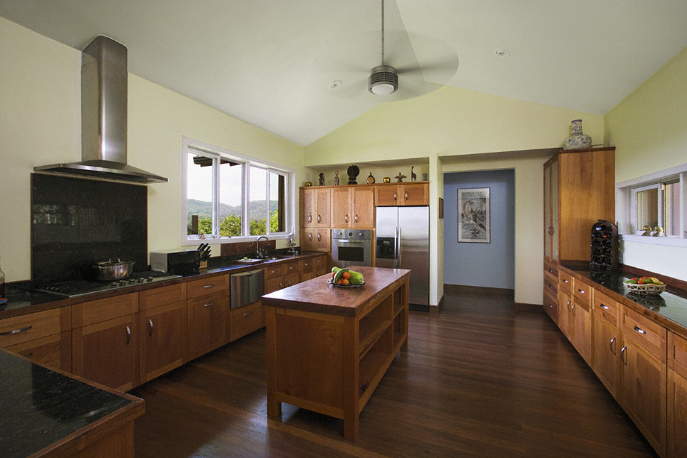 Design ideas for a large tropical galley eat-in kitchen in New York with a drop-in sink, flat-panel cabinets, medium wood cabinets, granite benchtops, black splashback, stainless steel appliances, medium hardwood floors and with island.