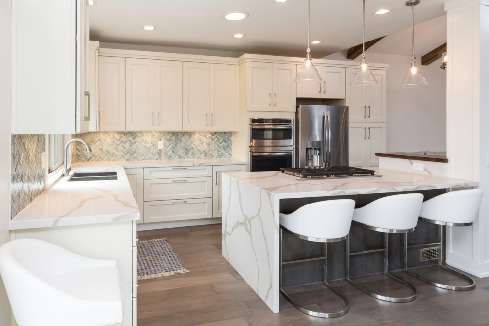 Inspiration for a large transitional l-shaped dark wood floor eat-in kitchen remodel with an undermount sink, shaker cabinets, white cabinets, quartz countertops, blue backsplash, glass tile backsplash, stainless steel appliances, an island and white countertops