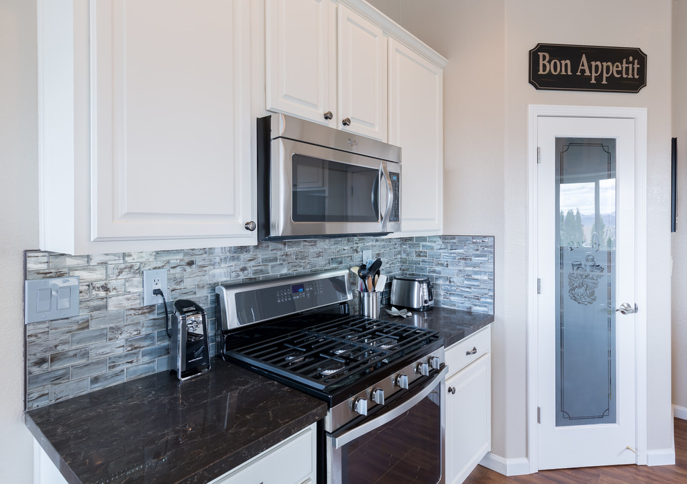 Inspiration for a mid-sized transitional u-shaped eat-in kitchen remodel with a single-bowl sink, raised-panel cabinets, white cabinets, quartzite countertops, gray backsplash, glass tile backsplash, stainless steel appliances and an island