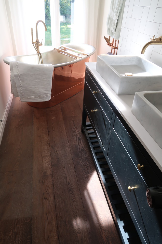Design ideas for a mid-sized traditional master bathroom in Sussex with furniture-like cabinets, black cabinets, a freestanding tub, a shower/bathtub combo, white walls, dark hardwood floors, a console sink, engineered quartz benchtops, brown floor and white benchtops.