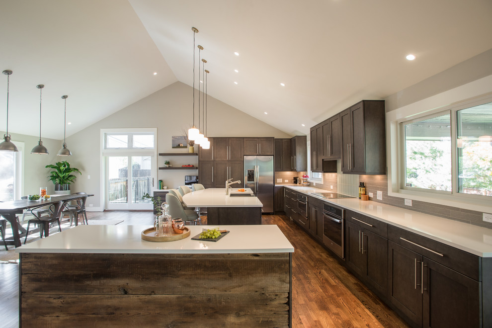 Large transitional l-shaped dark wood floor open concept kitchen photo in Denver with a farmhouse sink, shaker cabinets, dark wood cabinets, beige backsplash and two islands